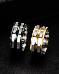 Two modern multi-band rings with a hexagonal design, one in silver-tone metal and the other in gold-tone metal, displayed on a textured black surface.