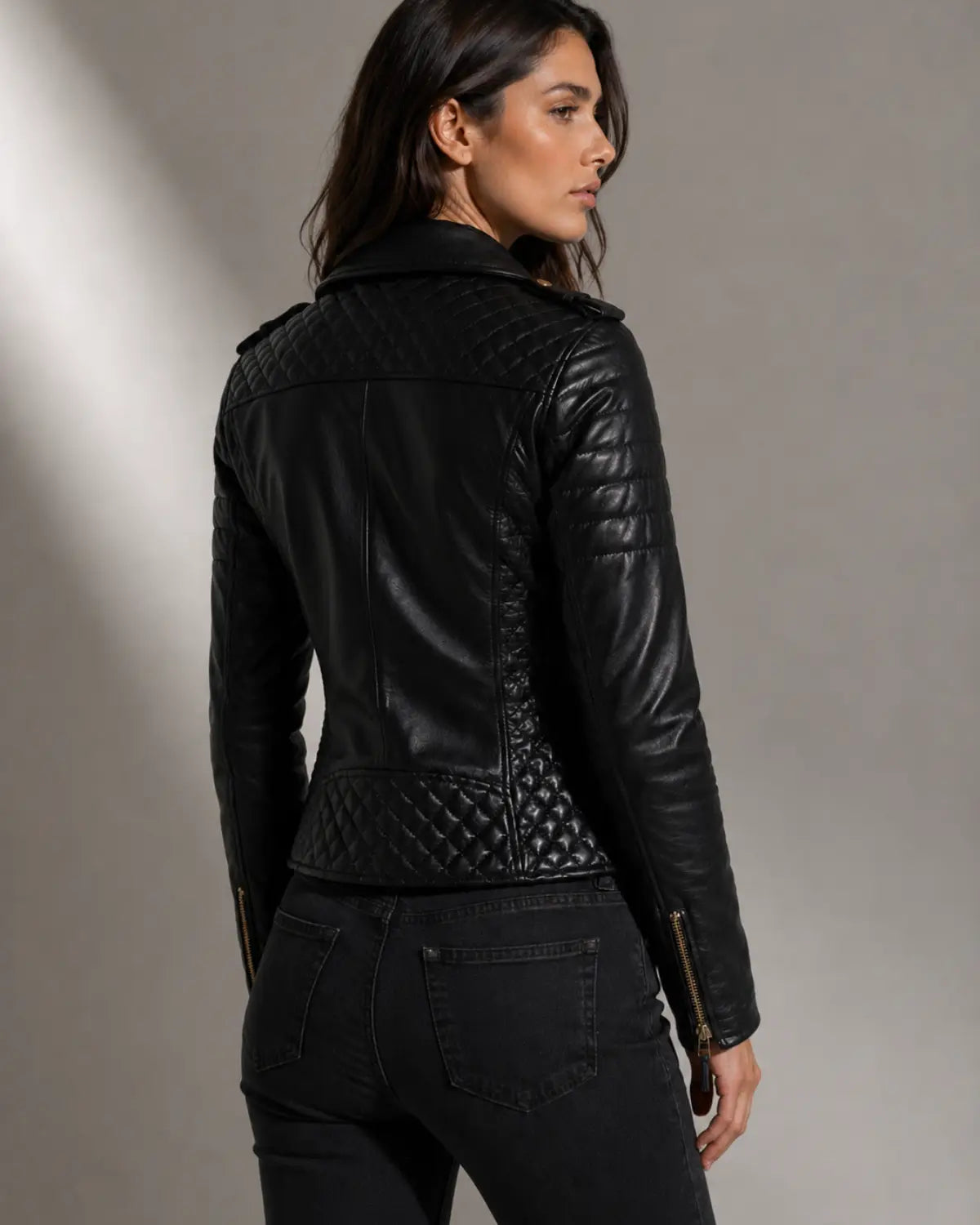 Woman wearing a black  lamb leather biker  jacket with gold zippers and poppers designed by Vannamoda