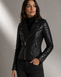 Woman wearing a black  lamb leather biker  jacket with gold zippers and poppers designed by Vannamoda
