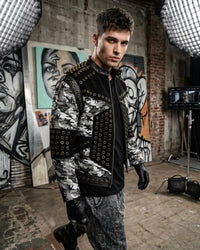 Man wearing a stylish jacket with camouflage pattern and black accents in an urban setting.