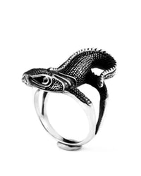 A silver-toned metal ring featuring a highly detailed, textured lizard or chameleon head and upper body wrapping around the band, set against a plain white background.