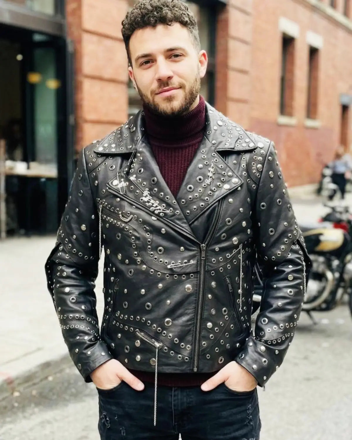 Man wearing a studded leather jacket on a city street.