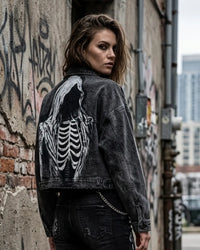Person wearing a black denim jacket with a skeleton design in an urban setting