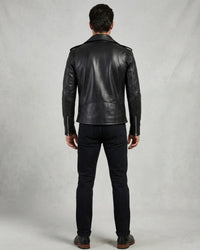 A man viewed from the back wearing a black leather biker jacket, black pants.