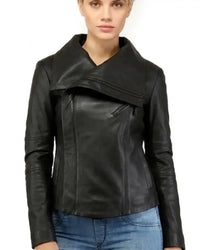 A woman wearing a black leather jacket with an asymmetrical wrap-style front and blue jeans, photographed against a plain white background.