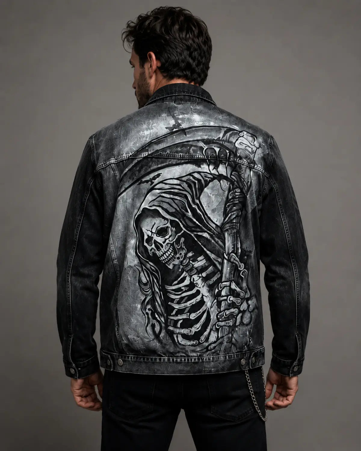 Hand-painted black acid wash denim jacket featuring a detailed grim reaper graphic on the back, shown on a male model