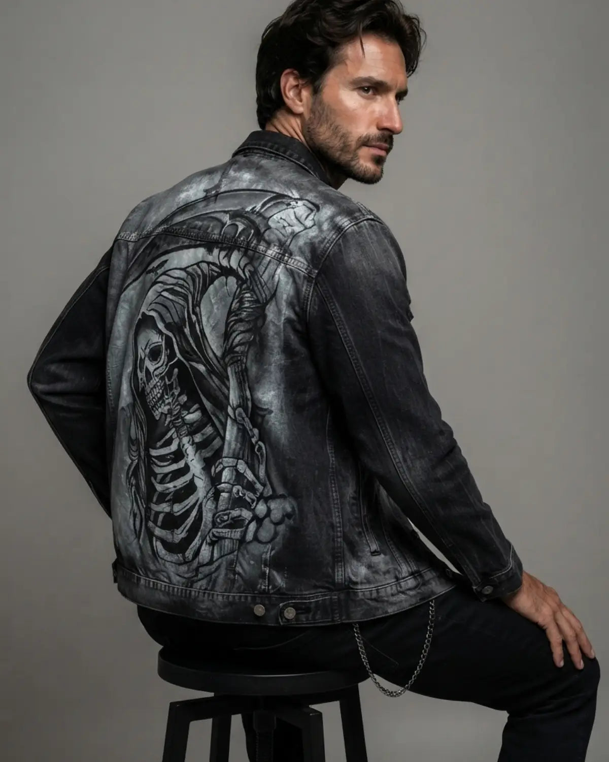 Hand-painted black acid wash denim jacket featuring a detailed grim reaper graphic on the back, shown on a male model